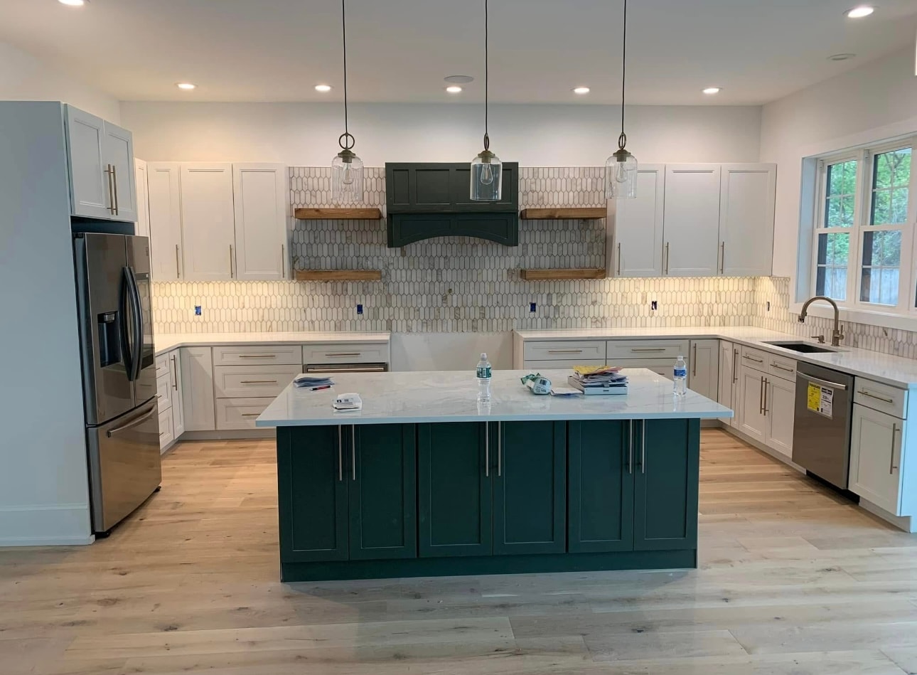 Custom kitchen with dark green island geometric tile backsplash and pendant lighting